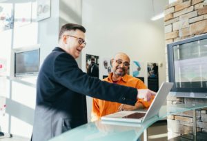 Zwei Kollegen stehen vor einem Laptop und unterhalten sich